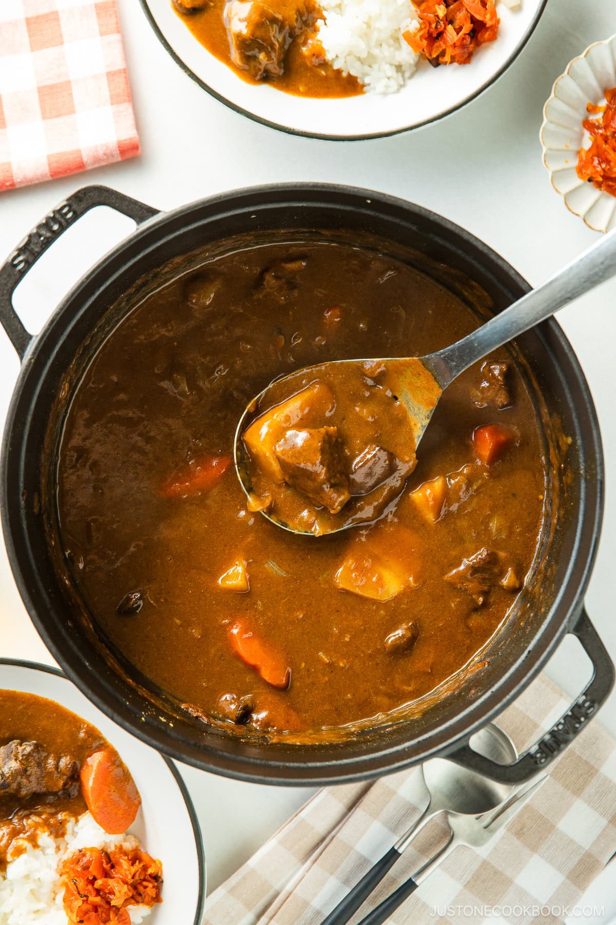 A black Staub containing Japanese beef curry, consisting of tender beef, potatoes, carrots, mushrooms, and curry roux.