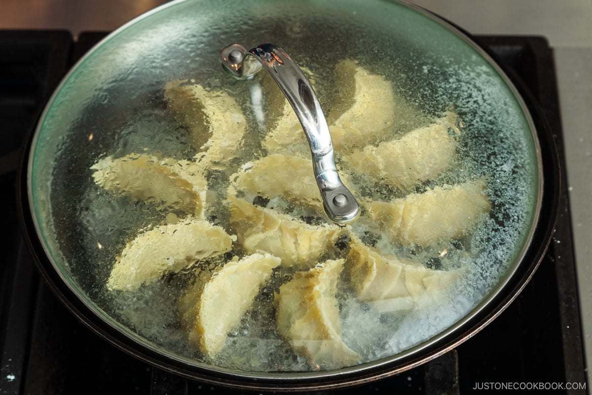 Steaming gyoza in the frying pan.