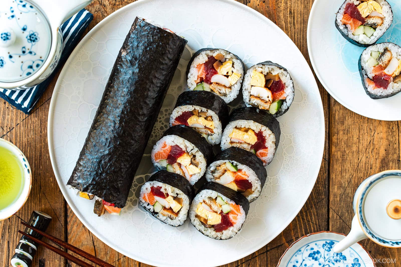 A round plate containing one ehomaki, or uncut sushi roll, and sliced sushi roll pieces, prepared for setsubun festival.