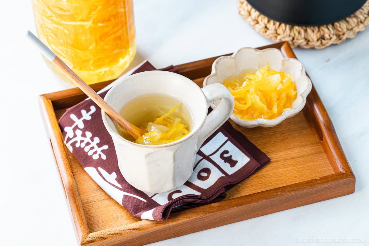 A wooden tray containing a cup and a small dish containing yuzu cha.