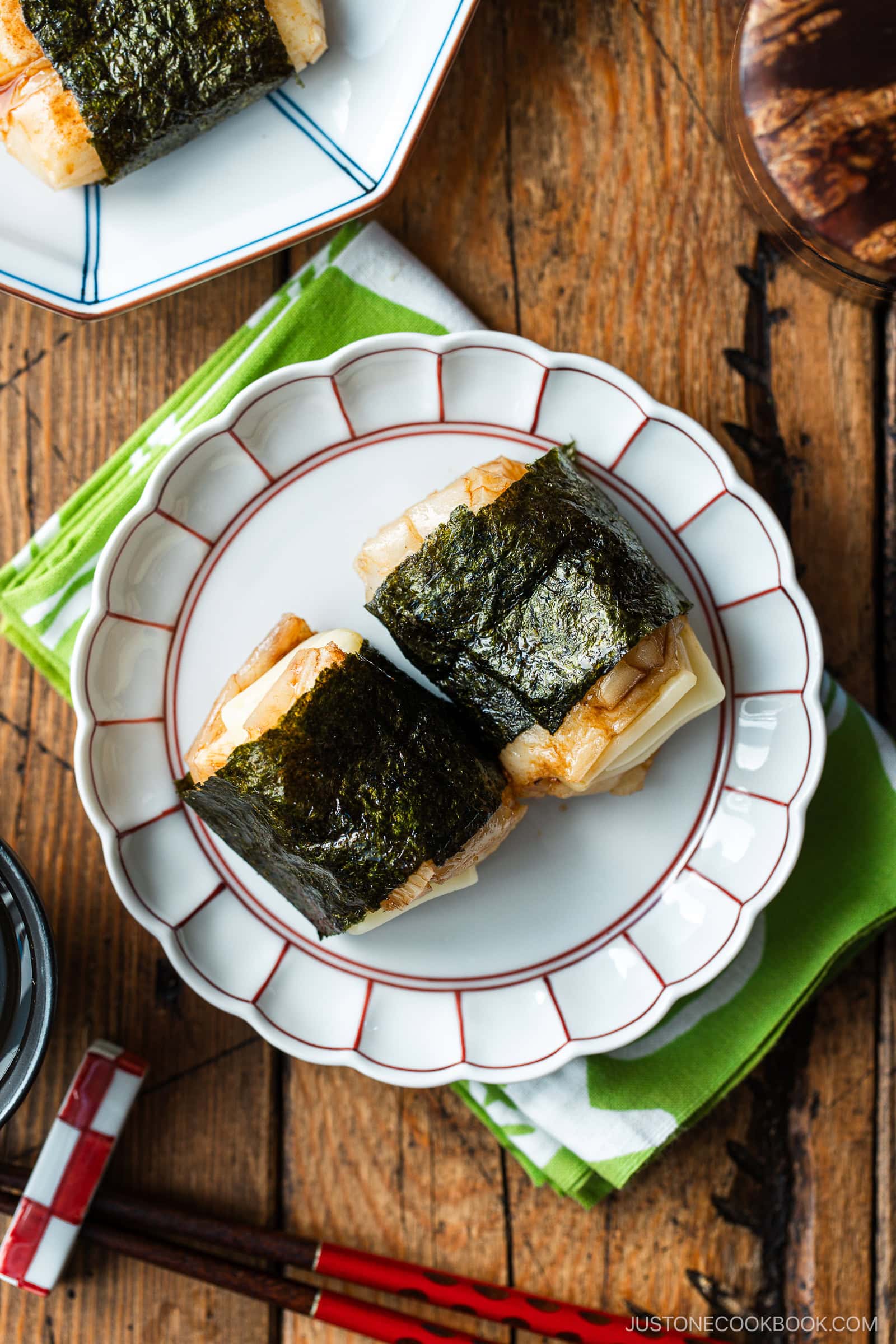 A round fluted plate containing cheese-stuffed Isobeyaki Mochi wrapped with nori seaweed.