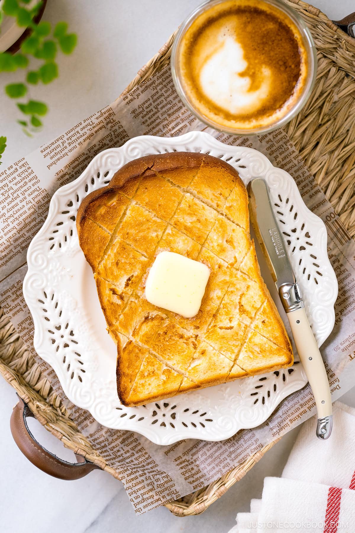 A perfectly toasted Japanese milk bread (shokupan) topped with melted butter on a white plate.