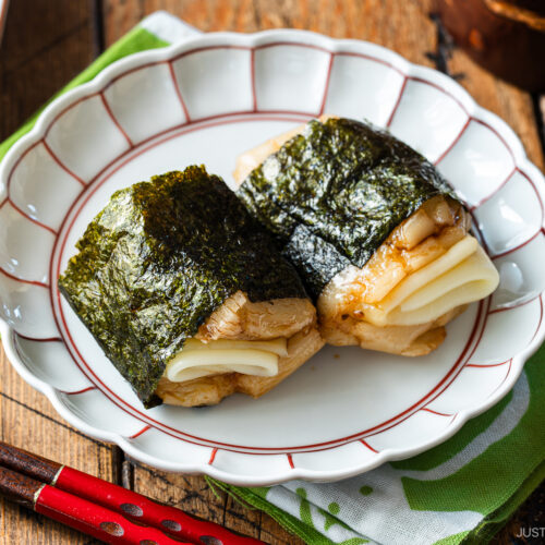 A round fluted plate containing cheese-stuffed Isobeyaki Mochi wrapped with nori seaweed.