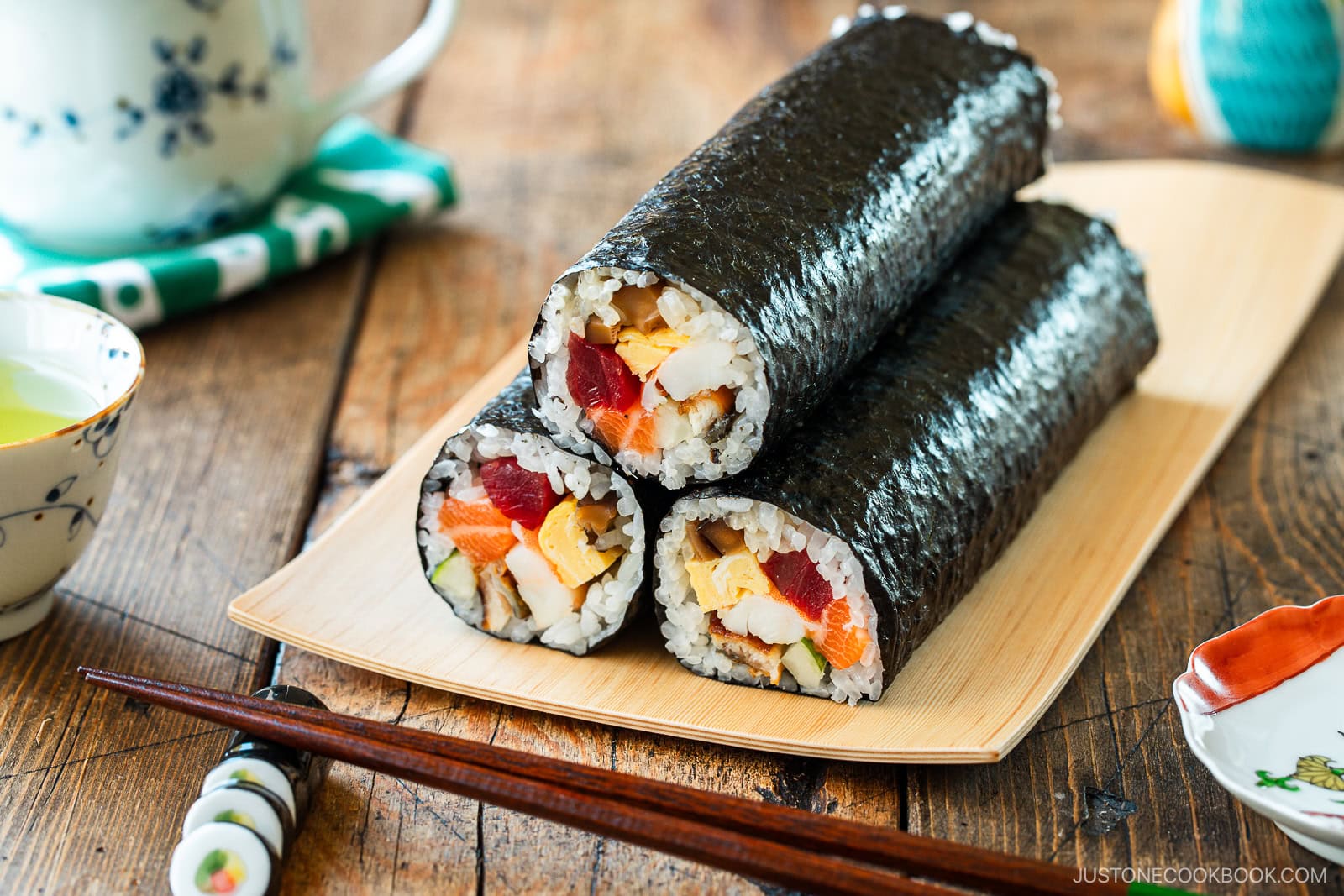 A rectangular plate containing three ehomaki, or uncut sushi rolls, prepared for setsubun festival.