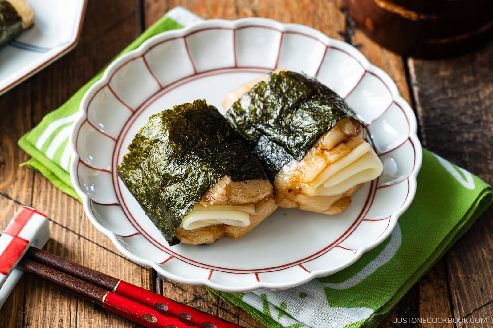 A round fluted plate containing cheese-stuffed Isobeyaki Mochi wrapped with nori seaweed.