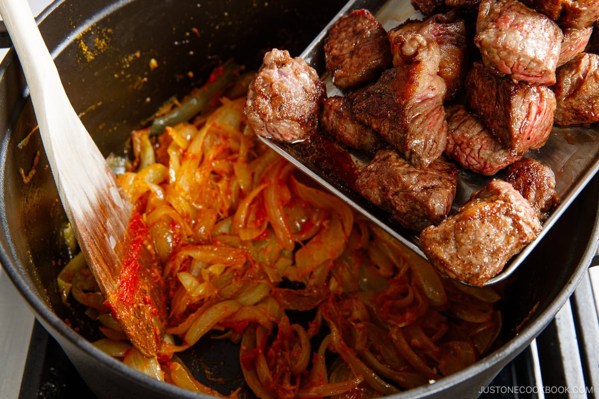 Adding beef to the pot.