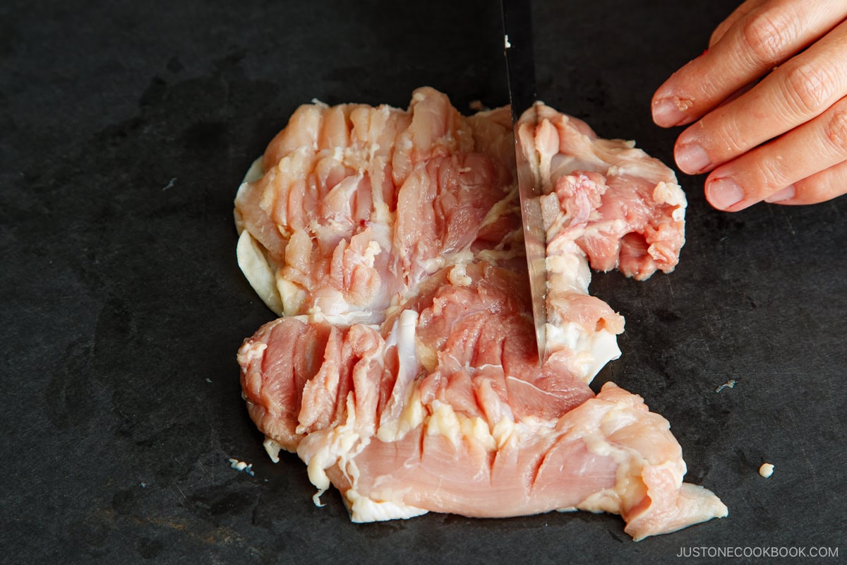 Make shallow cuts in the flesh across the entire chicken thigh, especially in the thickest parts.