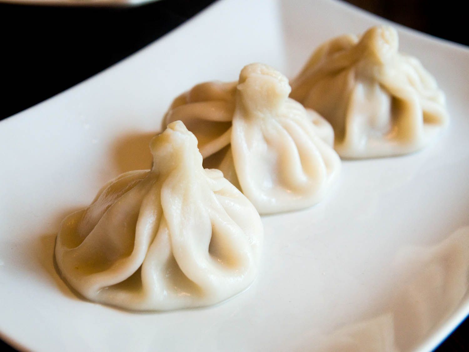 Three khinkali, Georgian soup dumplings, on a plate. 