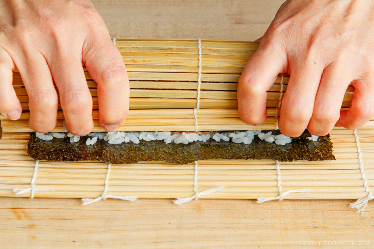 Gently squeeze the bamboo mat to make sure the sushi roll is tightly rolled.