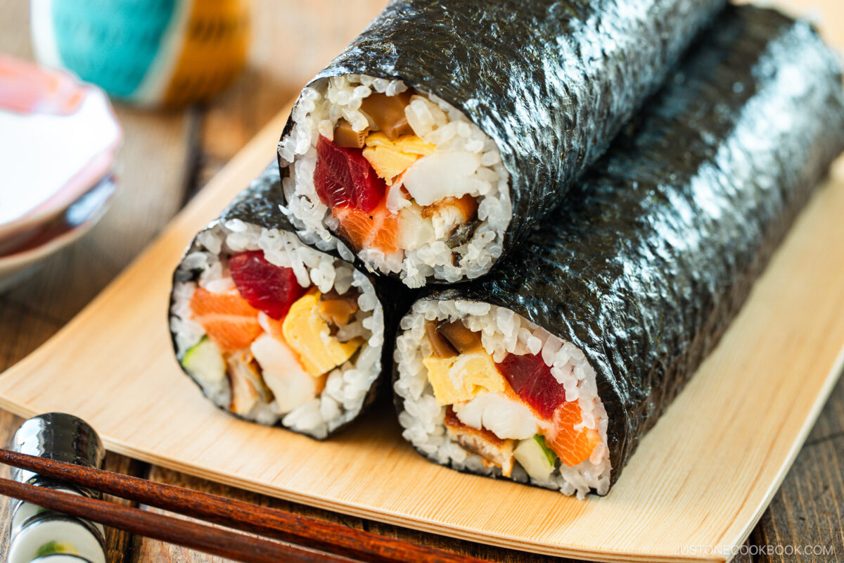 A rectangular plate containing three ehomaki, or uncut sushi rolls, prepared for setsubun festival.