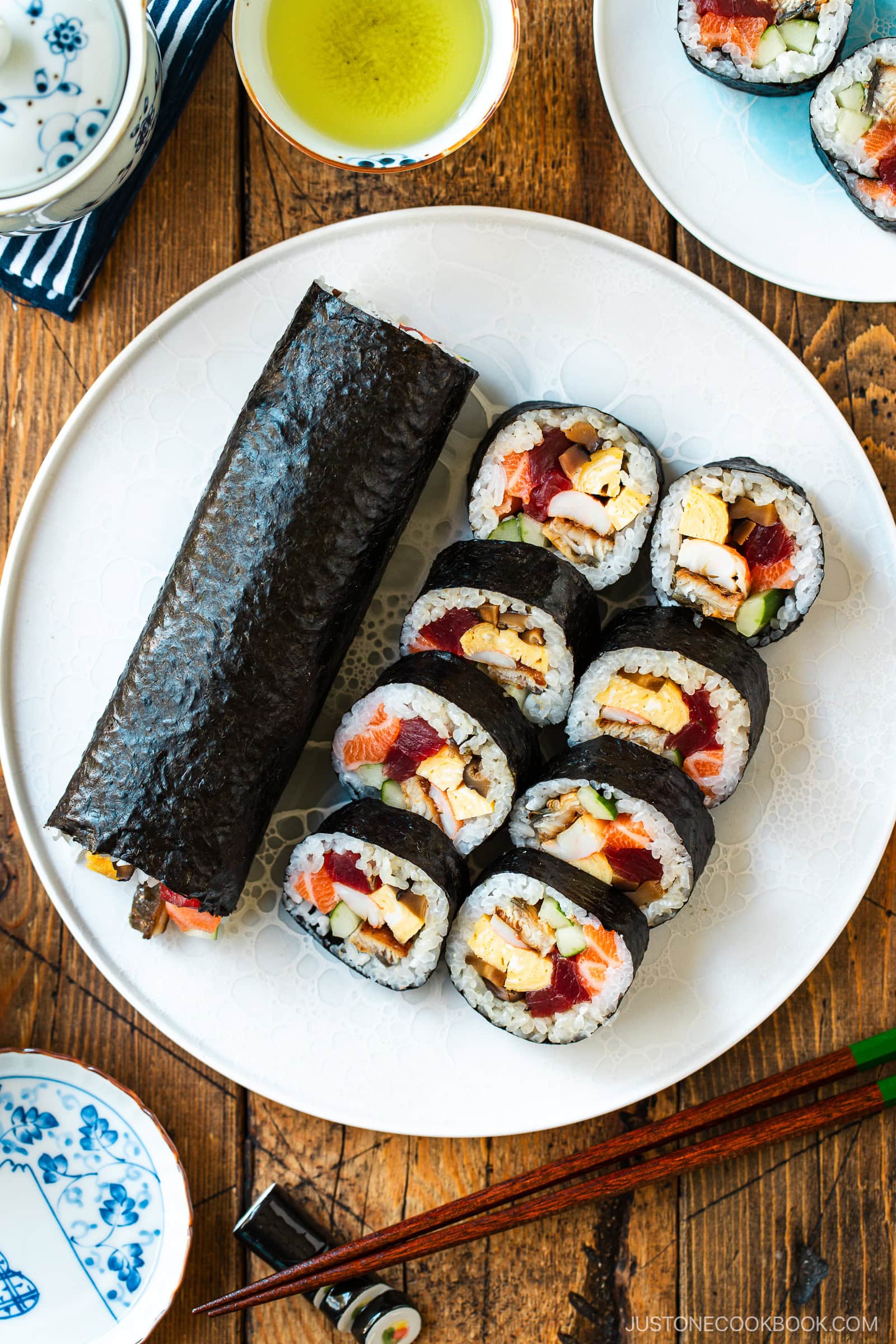 A round plate containing one ehomaki, or uncut sushi roll, and sliced sushi roll pieces, prepared for setsubun festival.