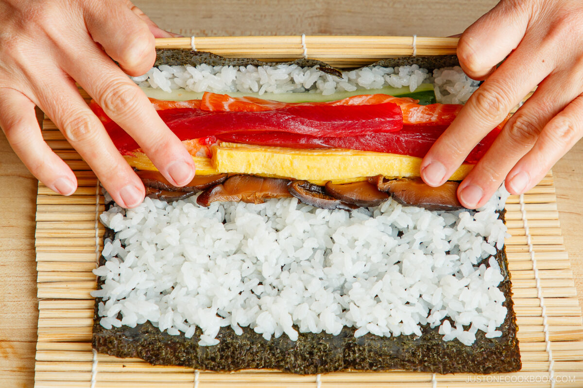 Rolling the sushi roll with the bamboo mat.