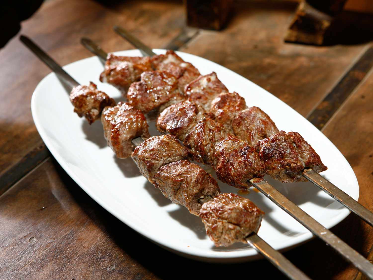 A platter holding three Mtsvadi skewers. 