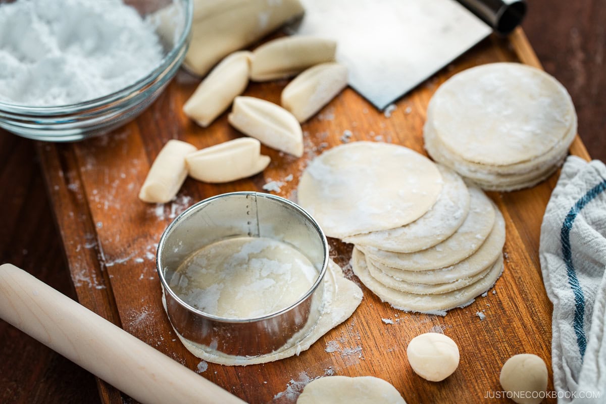 Homemade gyoza wrappers on a wooden cutting board.