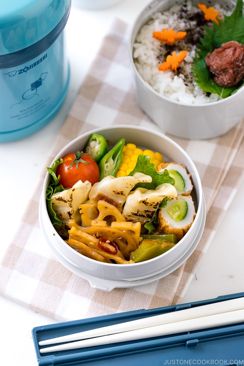 A Zojirushi lunch jar containing steamed rice, gyoza, and chikuwa cucumber.