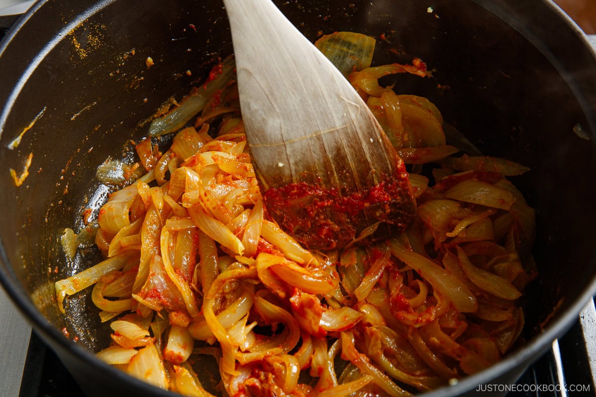 Add tomato puree and other seasonings to the caramelized onions.