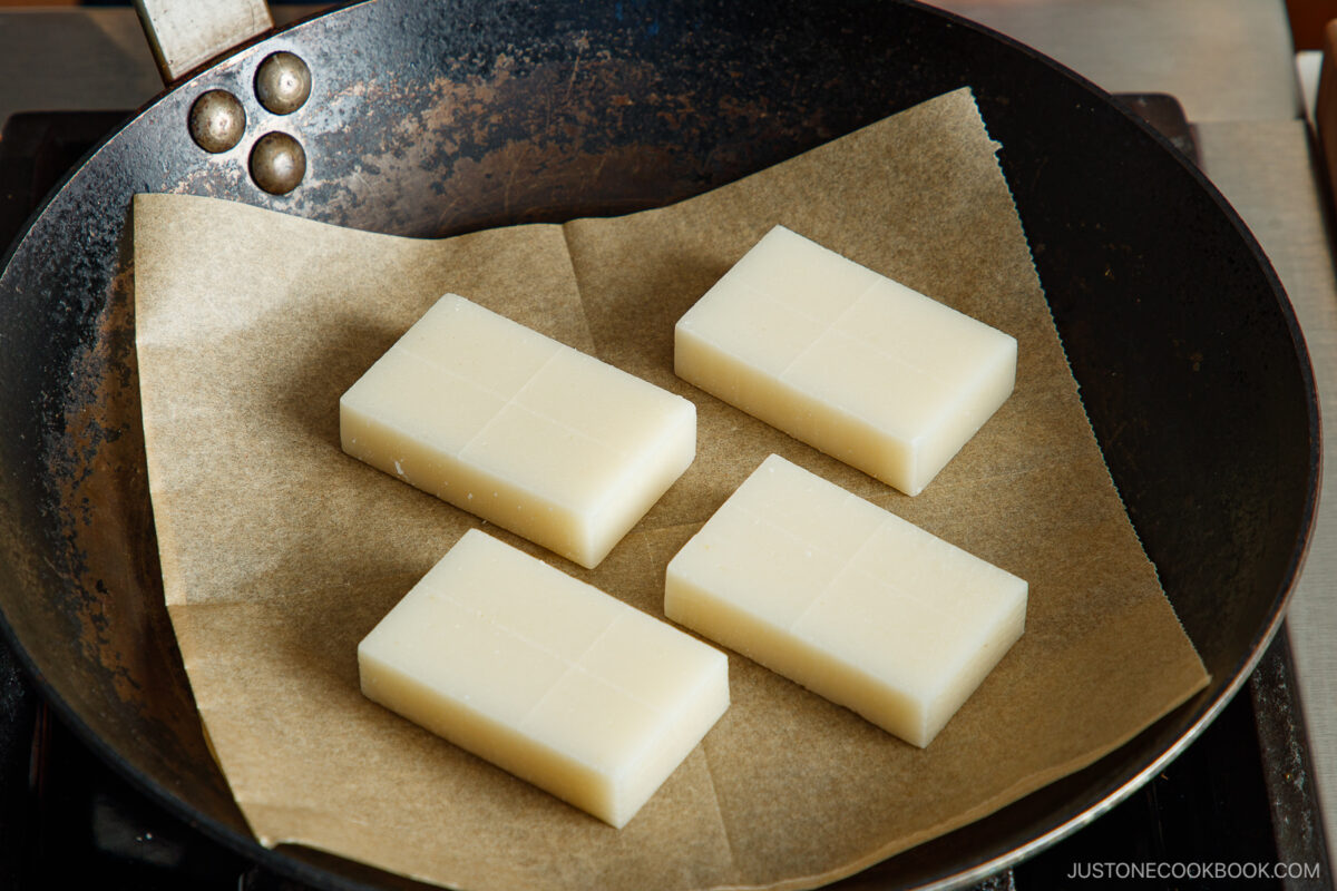 Place kiri mochi on a sheet of parchment paper in a frying pan.