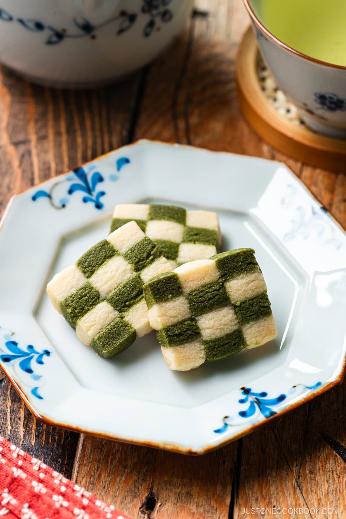 An octagonal plate containing Matcha Checkerboard Cookies served with a cup of green tea.