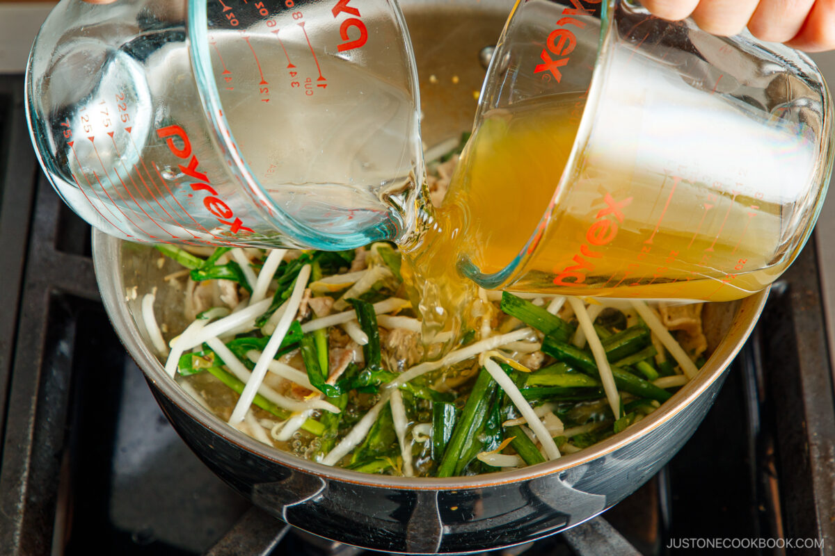 Adding the chicken stock and water to the pot.