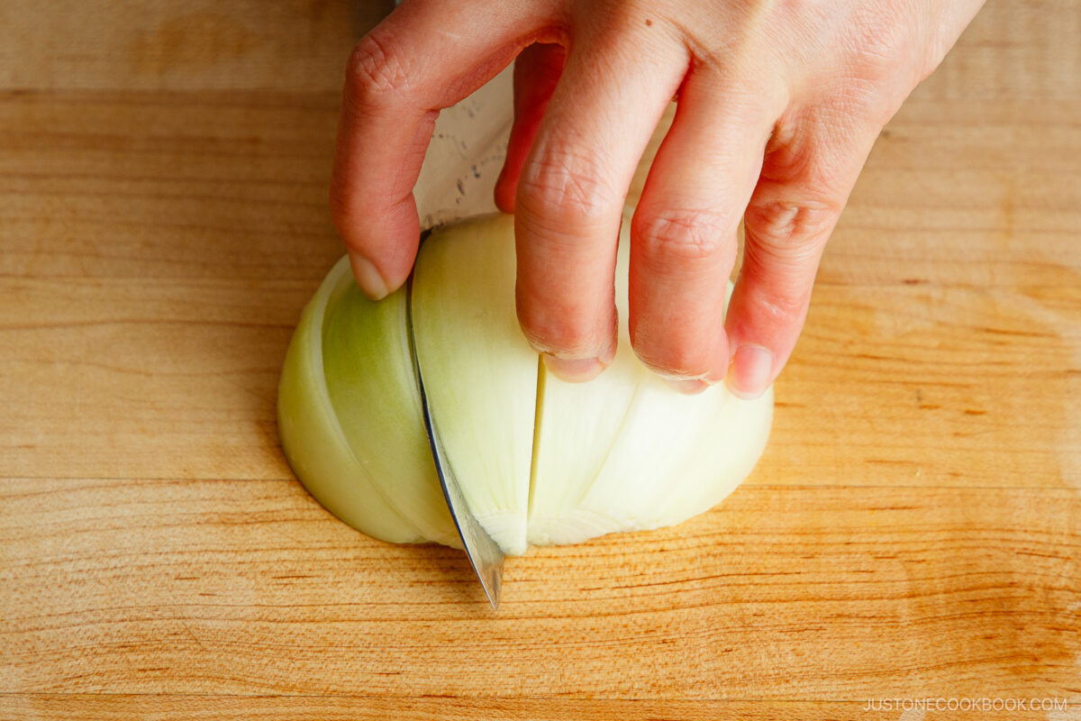 Cutting half the onion into wedges.