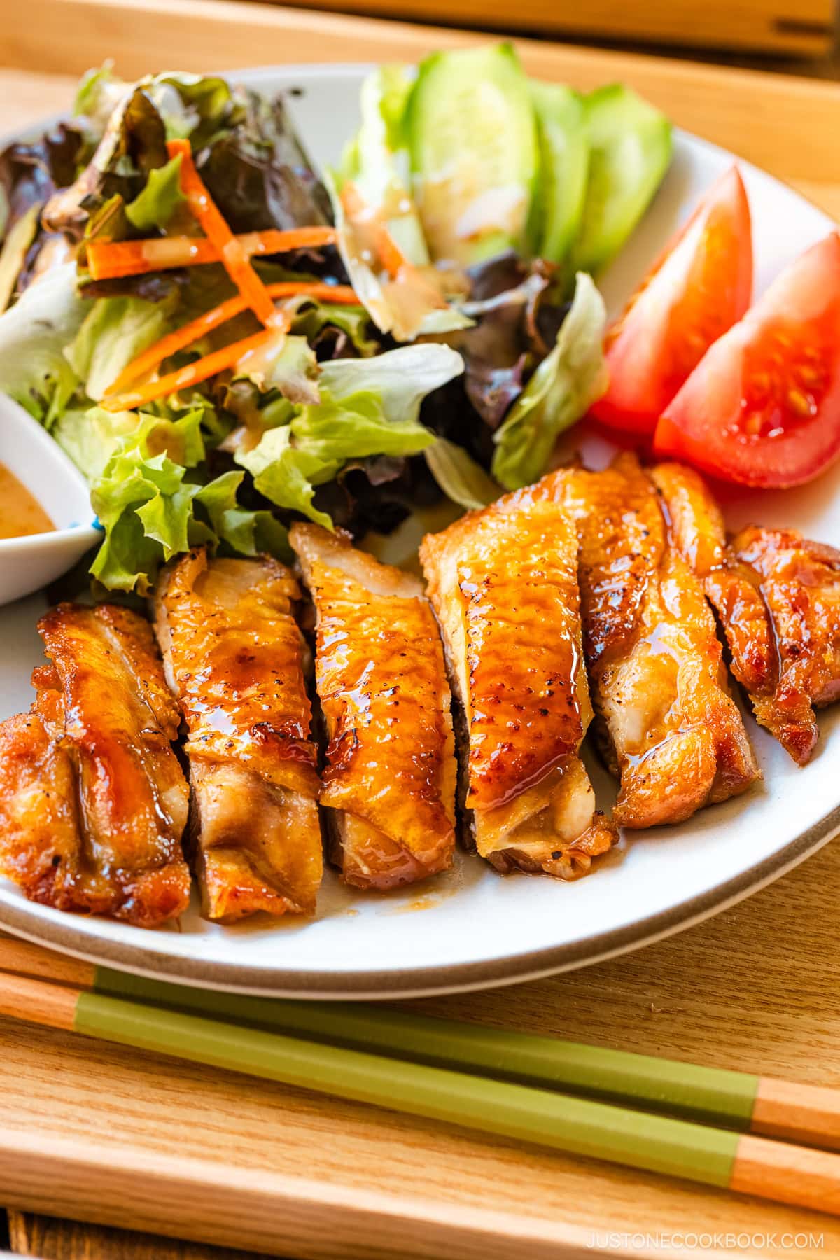 A round plate containing Chicken Teriyaki glazed with homemade teriyaki sauce.