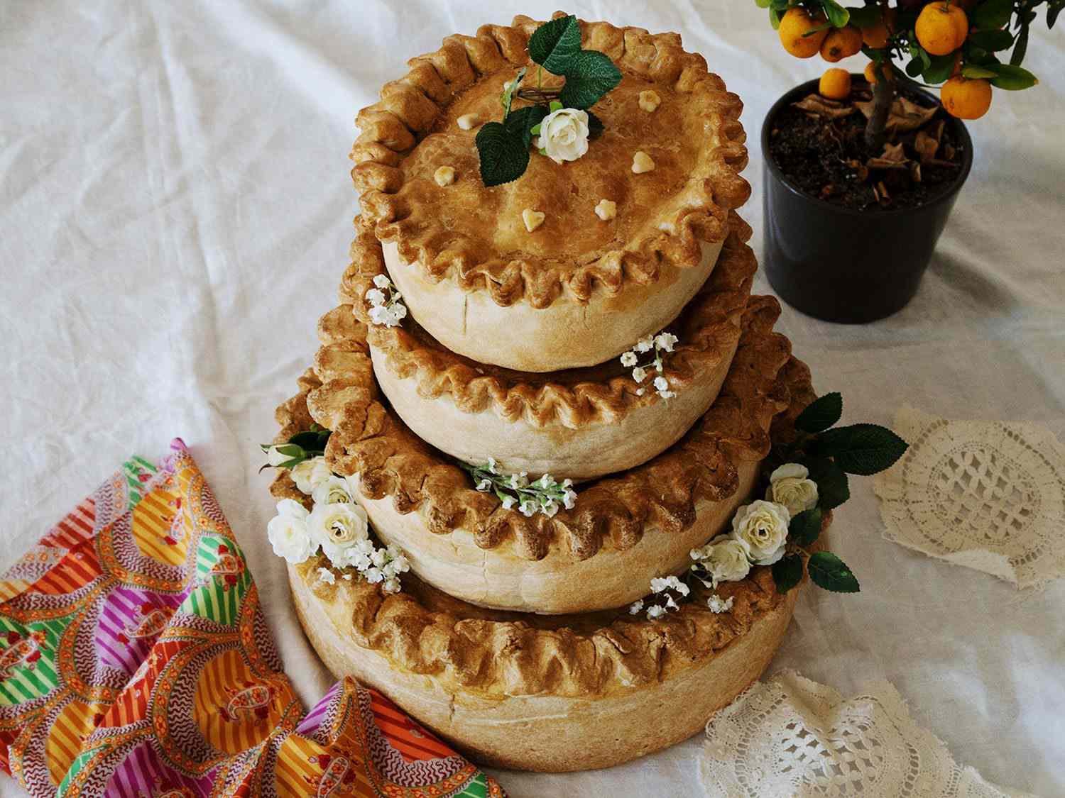A four-tiered pork pie for a wedding, decorated with flowers.