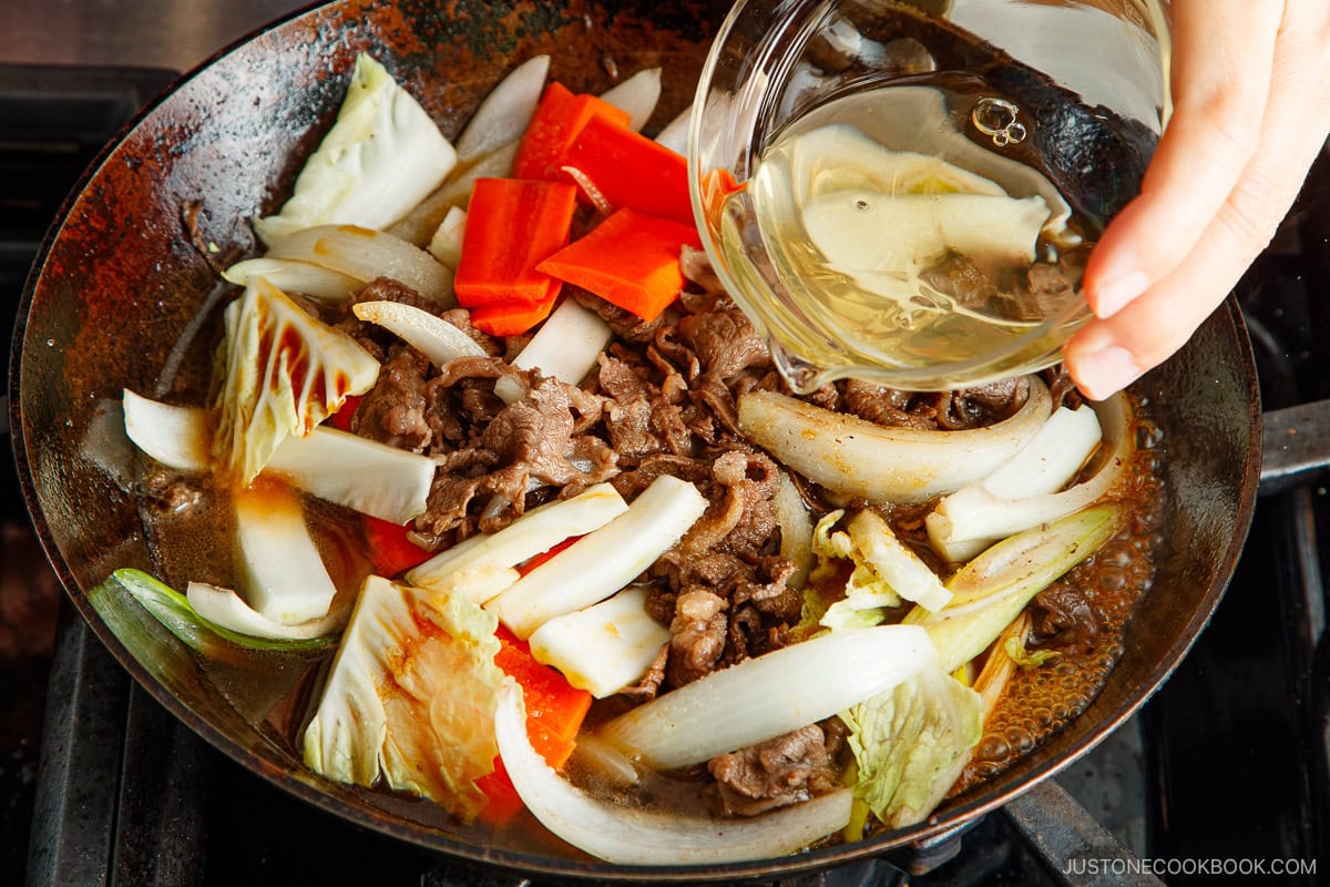 Addidng dashi to sukiyaki.