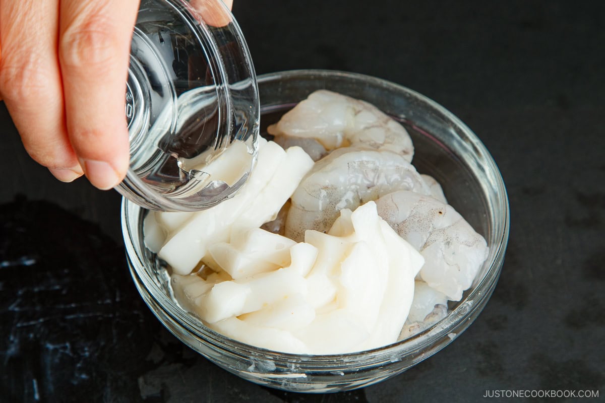 Adding sake to the seafood.