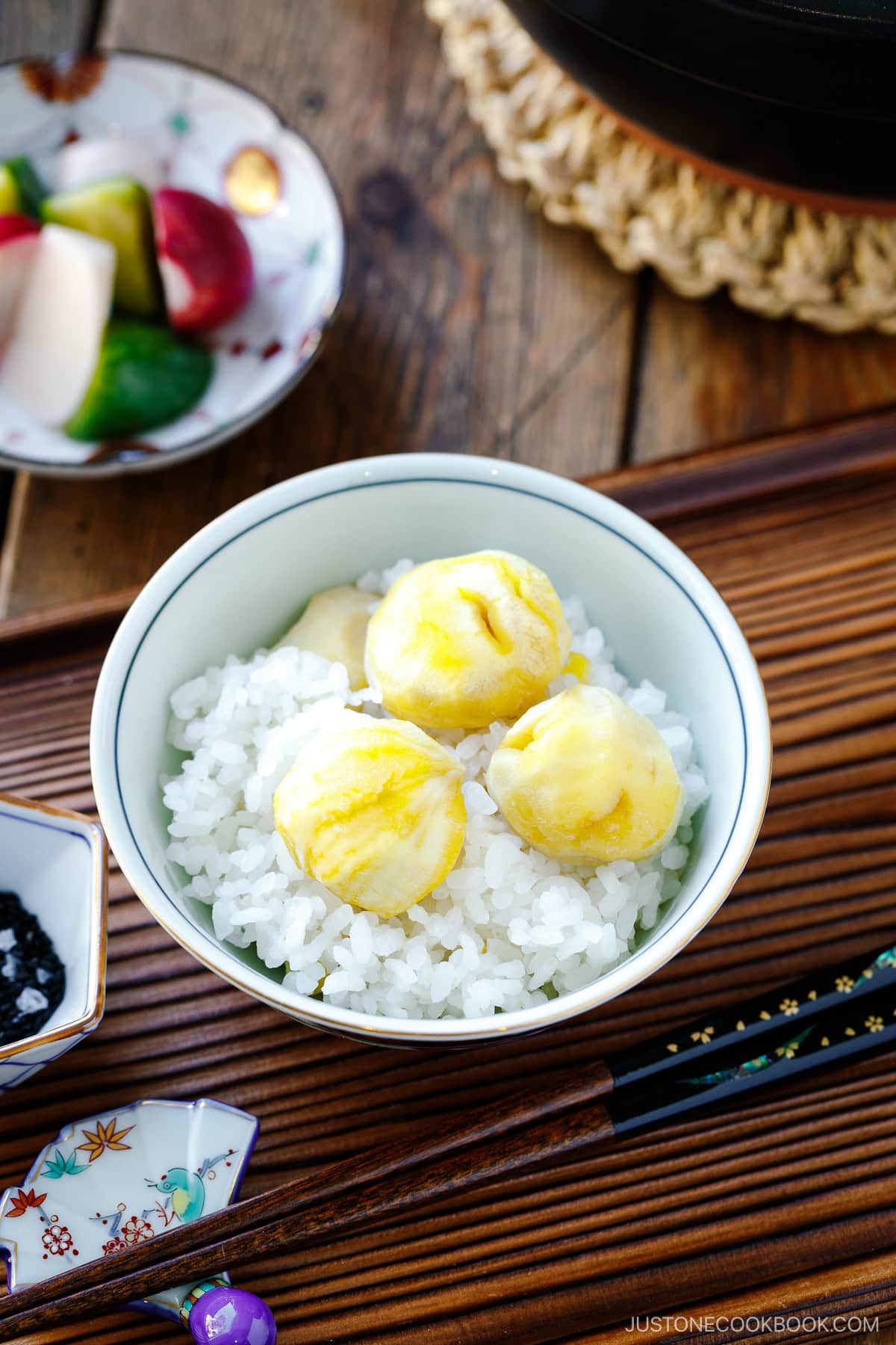 A rice bowl containing Japanese chestnut rice (kuri gohan), served with a little condiment bowl of black sesame seeds and salt.