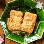 A green plate containing Japanese rice cake (mochi) coated with kinako (soybean flour).