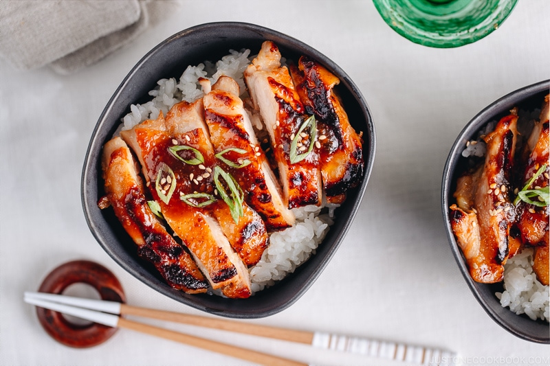 Miso chicken over steamed rice, garnished with sesame seeds and green onion.