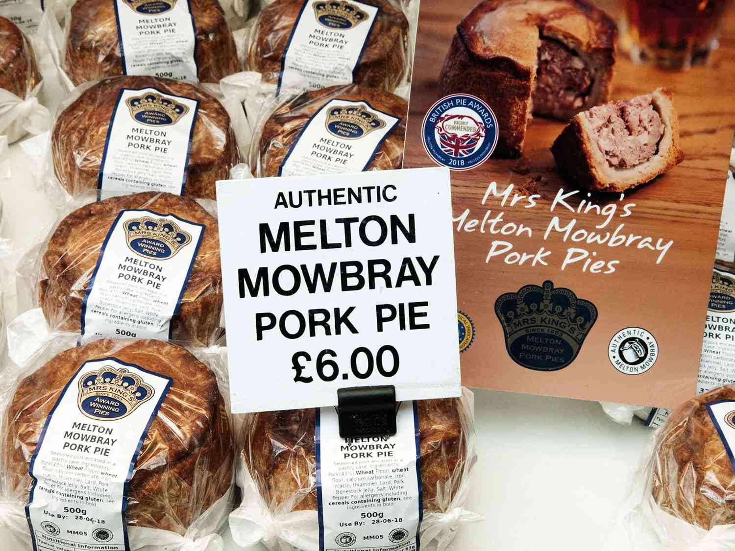 A display of wrapped pork pies for sale, with a sign that says "Authentic Melton Mowbray Pork Pie."