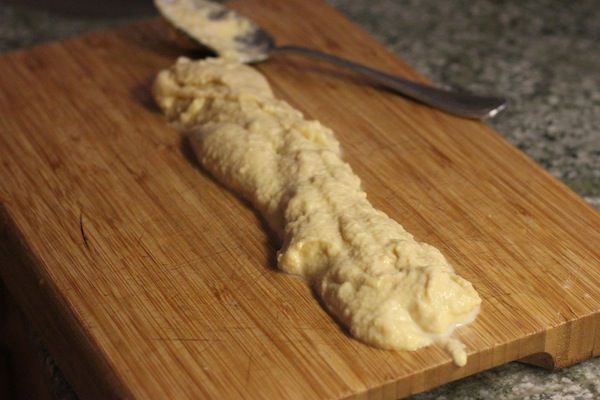 A portion of spatzle batter spread into a long strip along the cutting board.