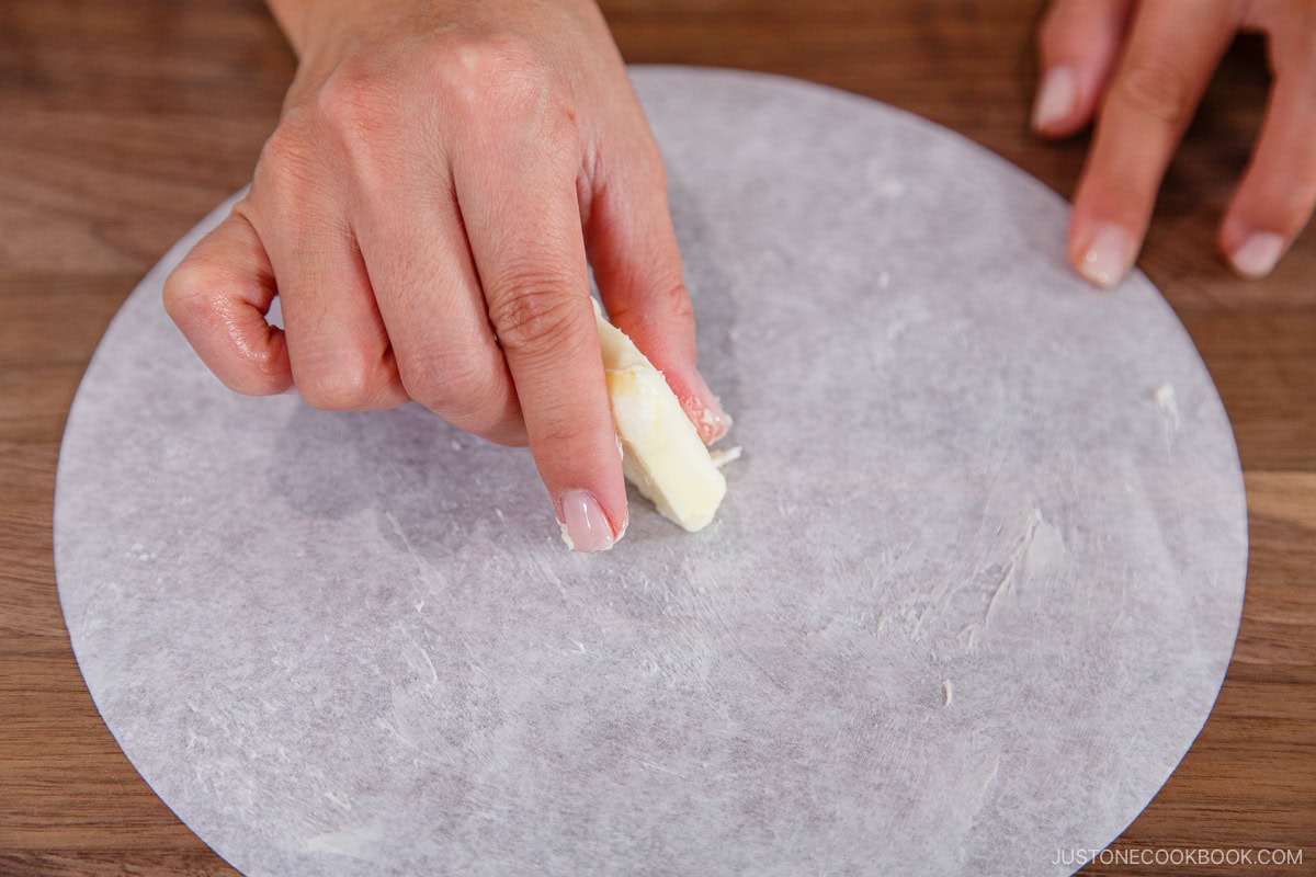 Greasing the parchment paper with butter.