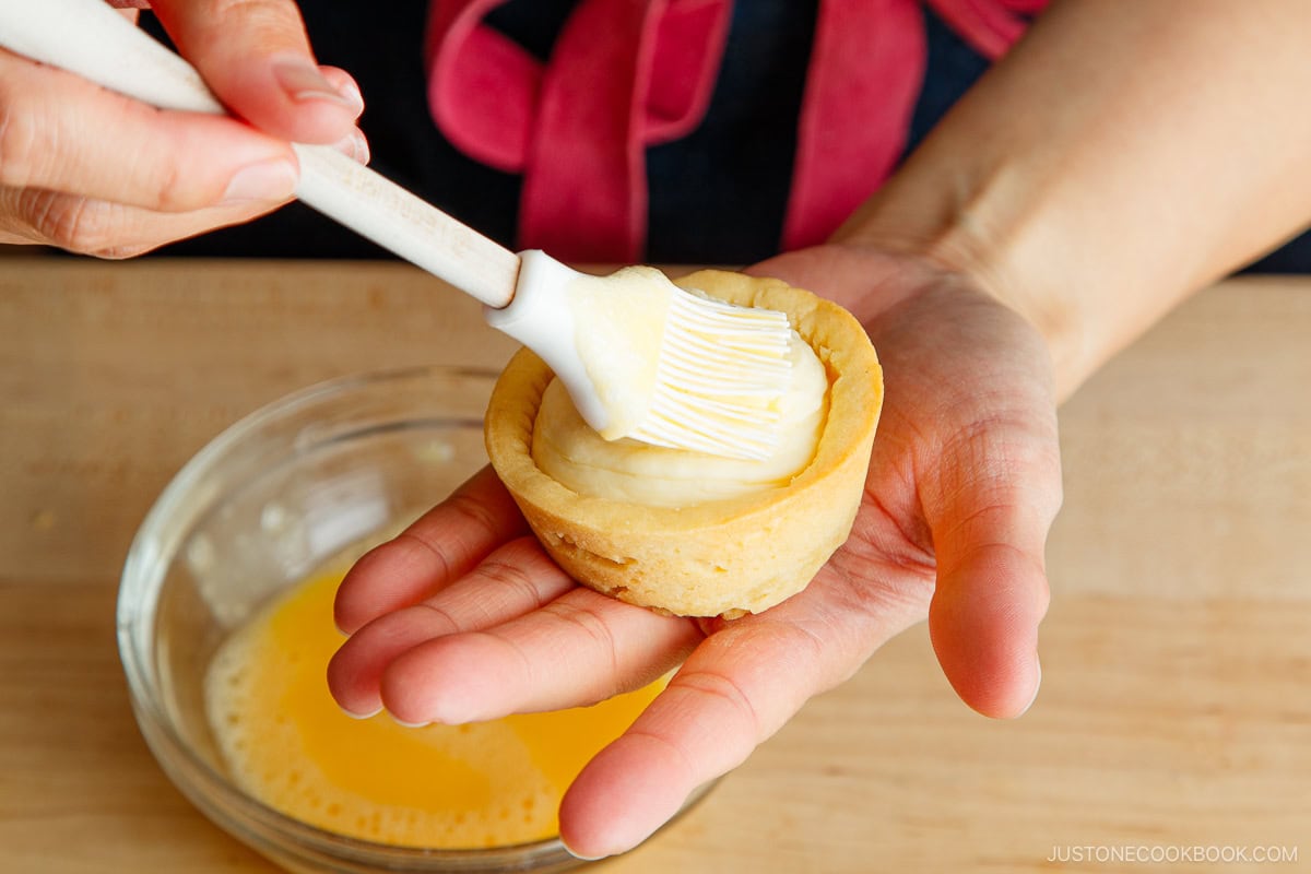 Brushing the cheese filling with egg wash.