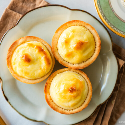 A flower shaped-plate containing baked cheese tarts.
