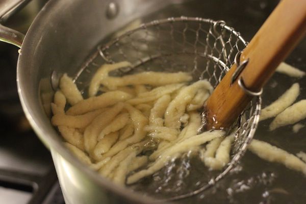 Author fishing out cooked spätzle with a spider skimmer.