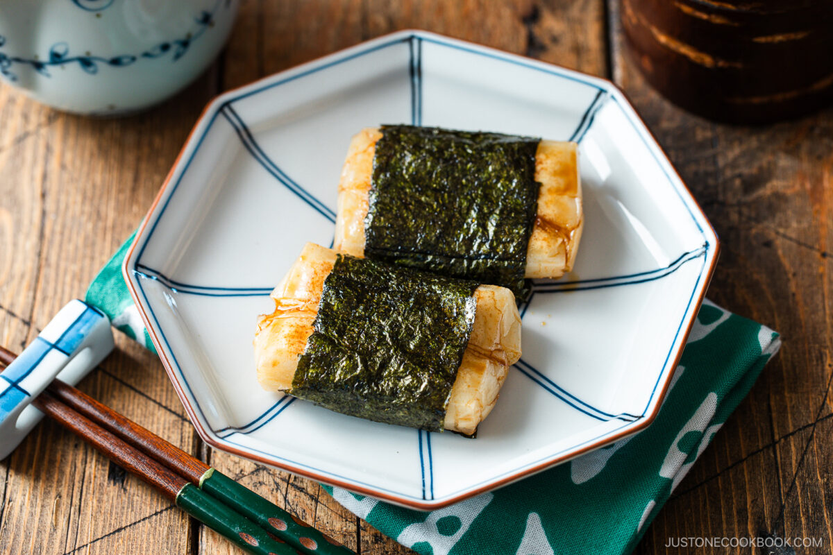 An octagon blue plate containing cheese-stuffed Isobeyaki Mochi wrapped with nori seaweed.