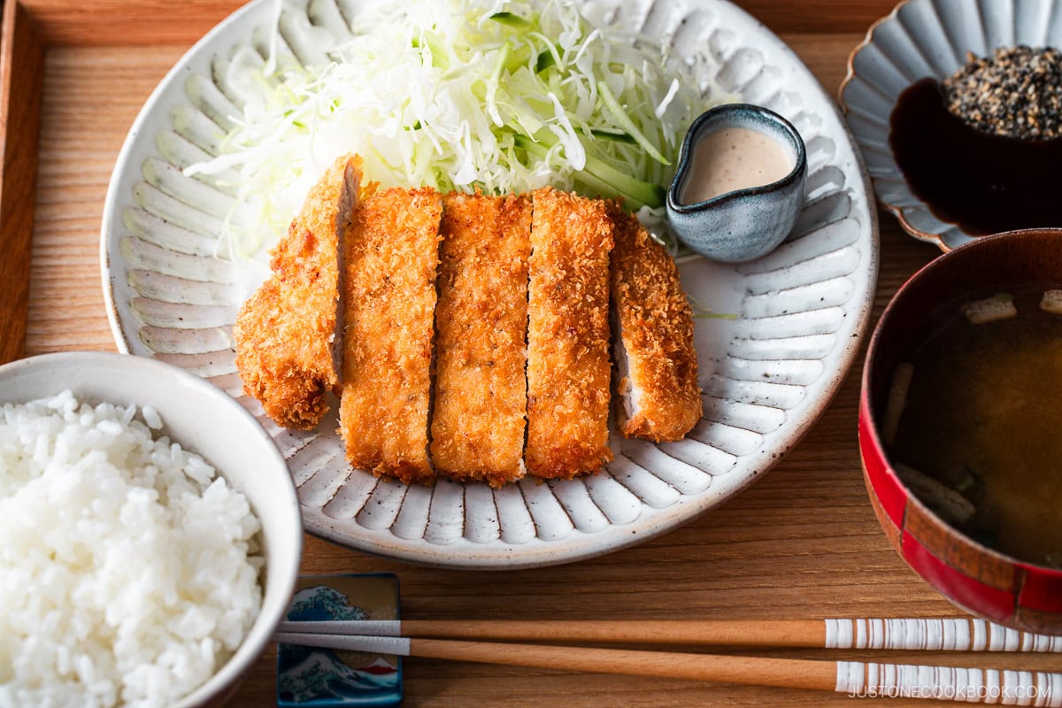 A Japanese ceramic plate containing Tonkatsu (pork cutlet) and shredded cabbage salad.