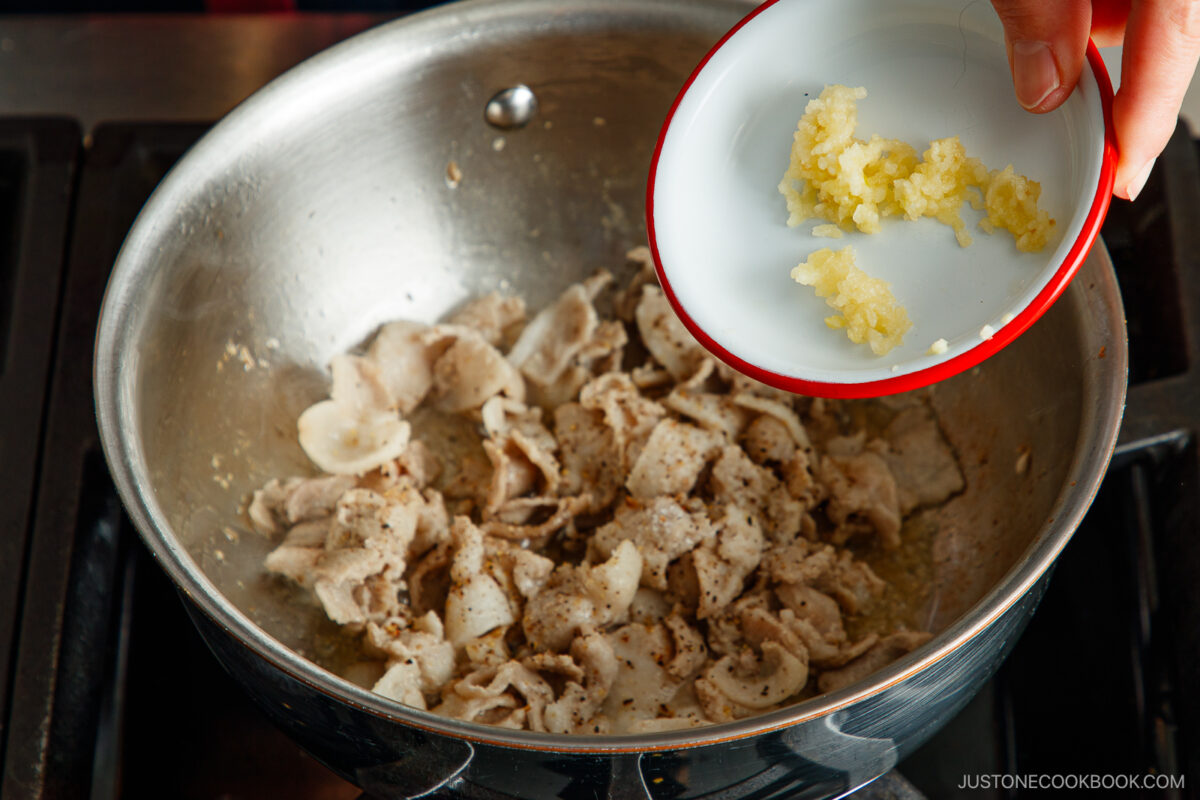 Adding the garlic to the pork belly.