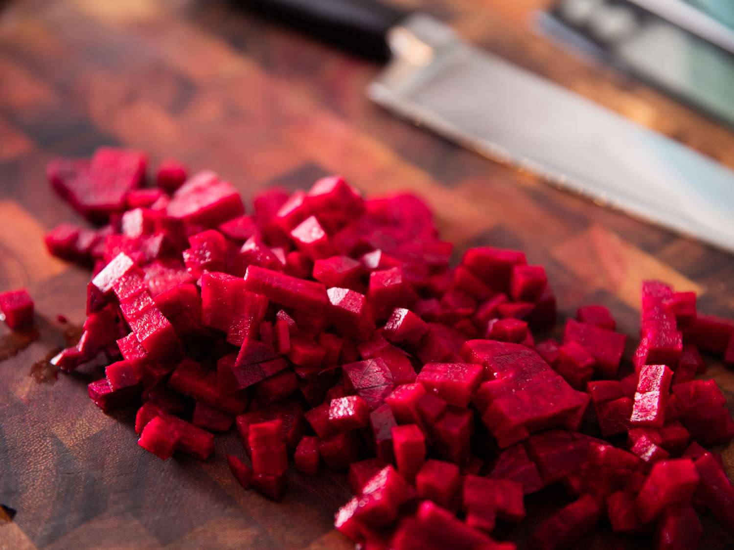 Diced raw beets on a wooden cutting board.