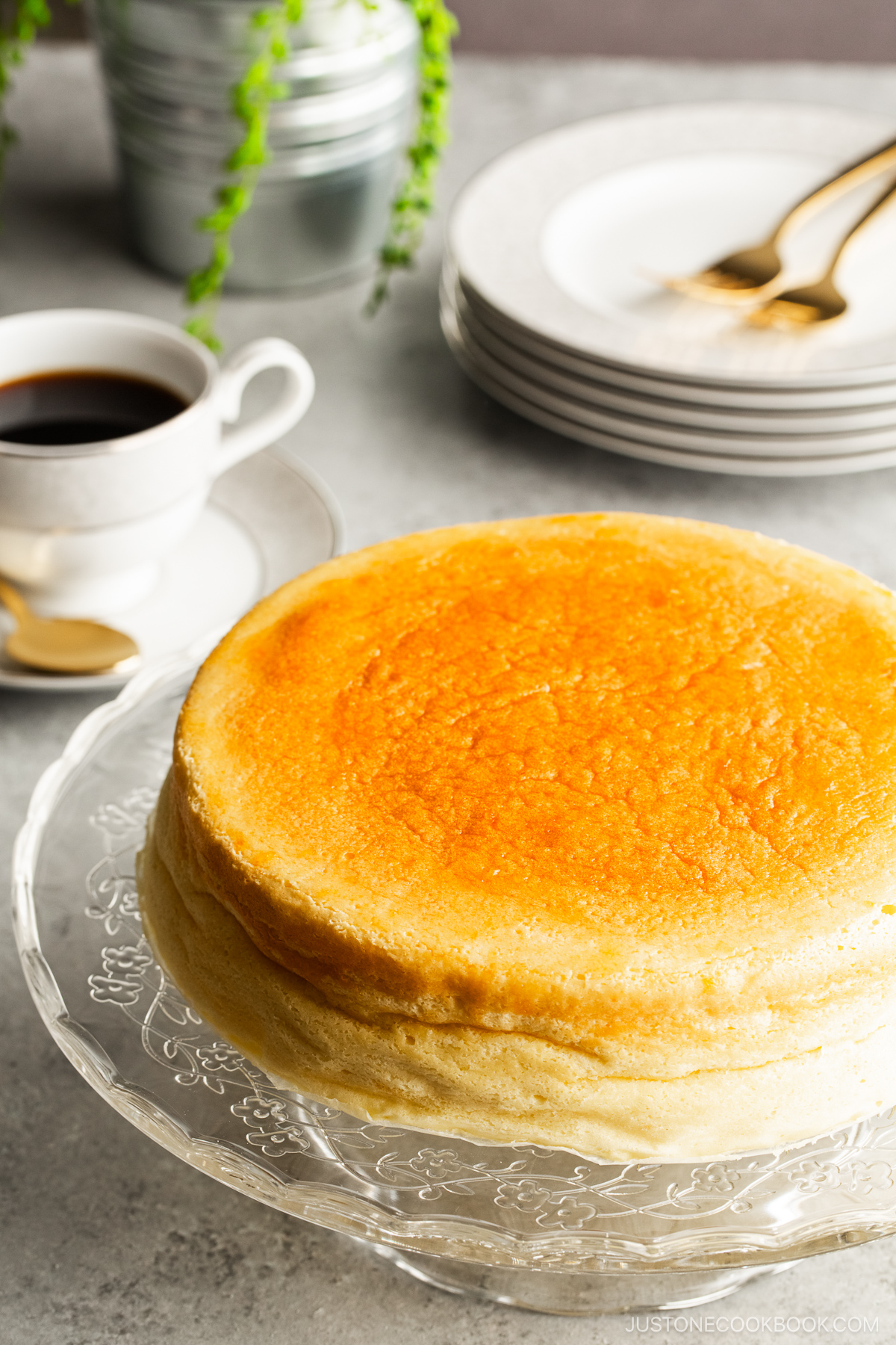 A glass cake stand containing a Japanese souffle cheesecake.