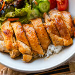 A bowl containing Chicken Teriyaki glazed with homemade teriyaki sauce on the bed of steamed rice.