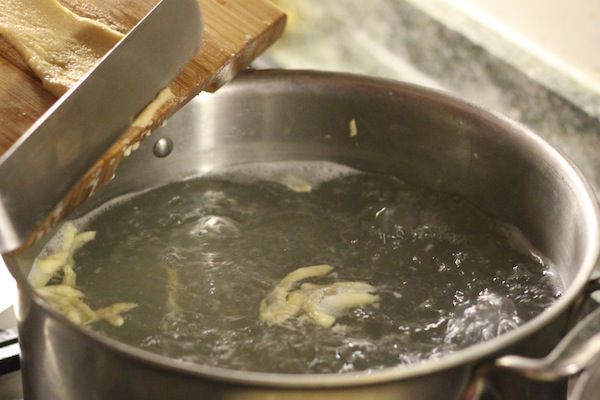 Cutting spätzle batter into thin strips to be boiled in water. 