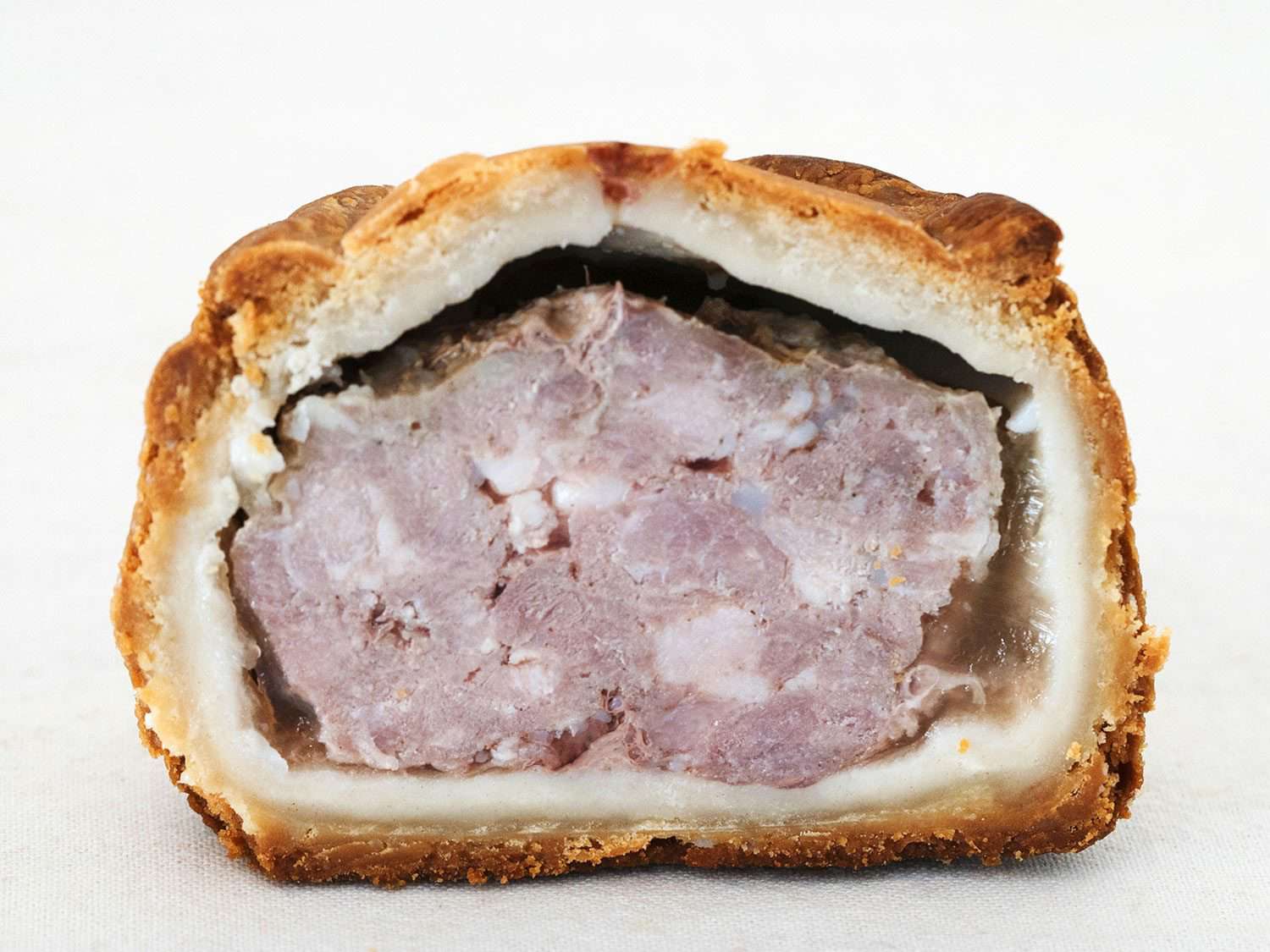 Interior of a Melton Mowbray pork pie, showing the meat filling, layer of jelly, and pastry crust outside