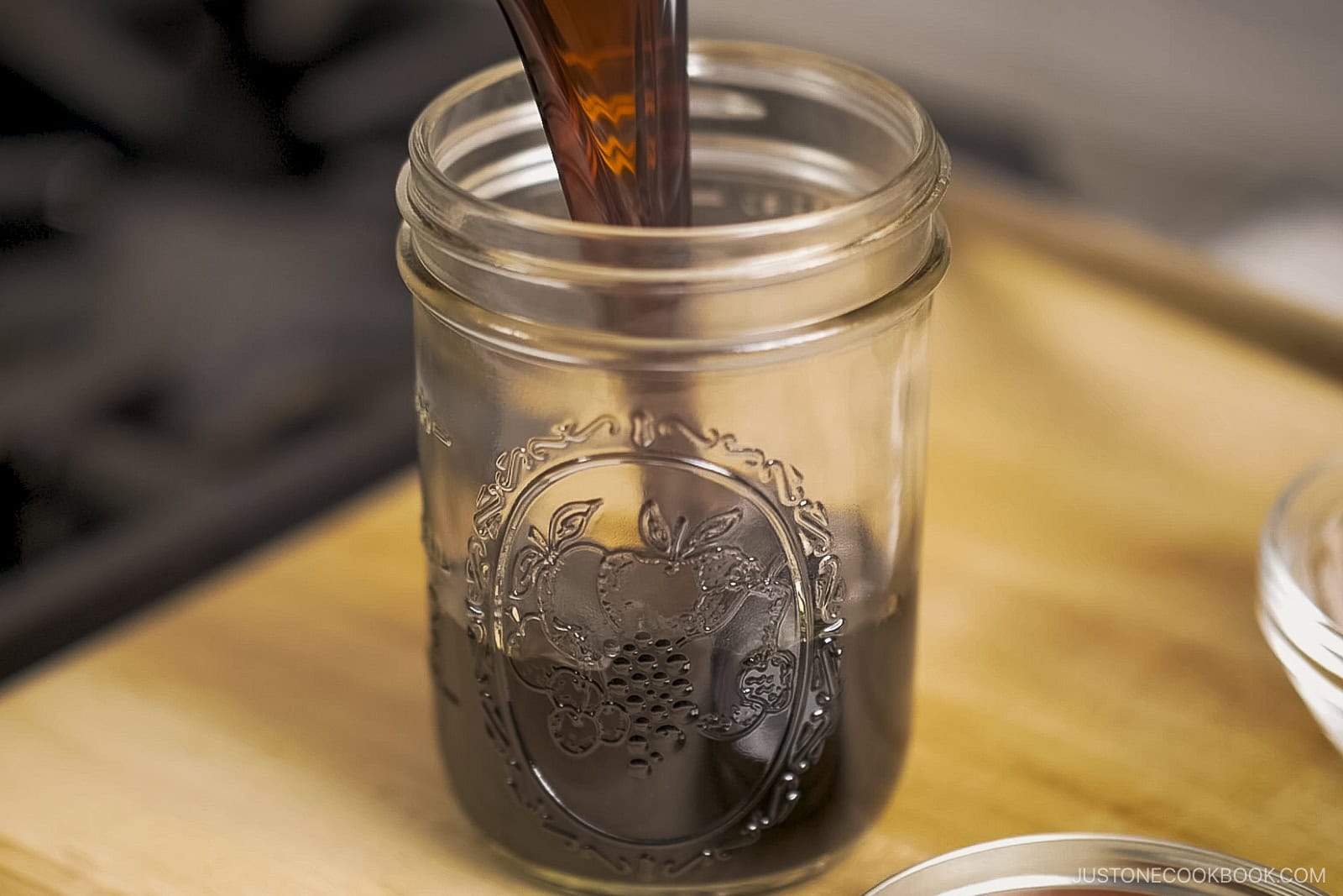 Pouring the teriyaki sauce into a mason jar.