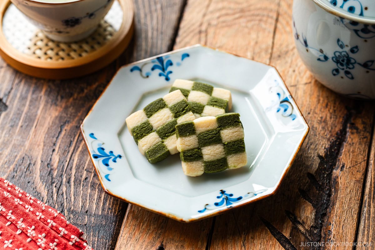 An octagonal plate containing Matcha Checkerboard Cookies served with a cup of green tea.