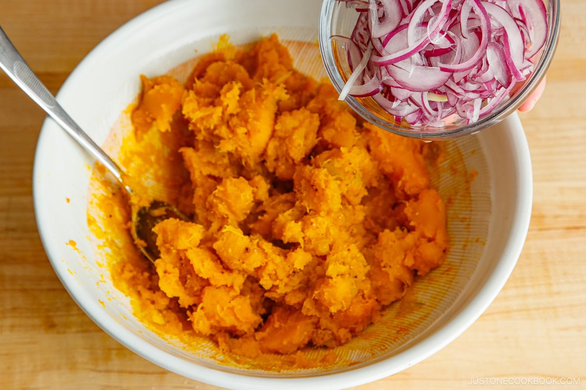 Addindg sliced red onions in a bowl.