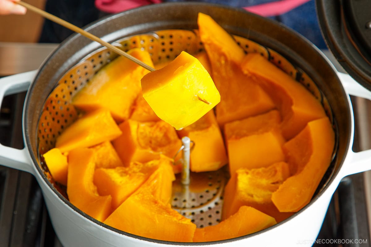 Checking doneness of steamed kabocha with a skewer.