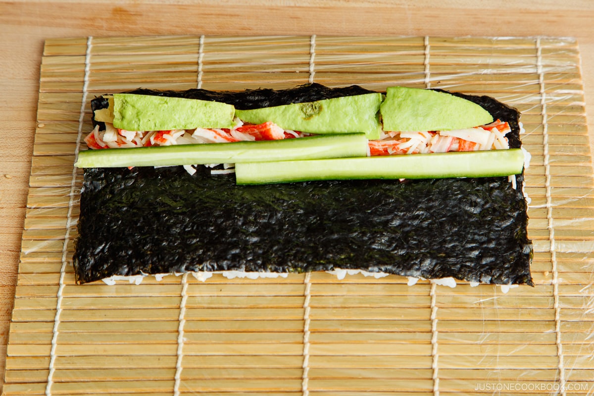 Place the crabmeat (loose ingredient first), avocado, and cucumber at the bottom of the nori sheet.